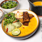 easy laksa recipe in a bowl with curry, tempeh, prawns, fish balls, bean sprouts, lime and noodles