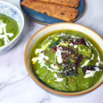 saag paneer in a bowl with paneer, spinach palak, curry leaves, spices, cream and chilli. Indian bread roti or naan.