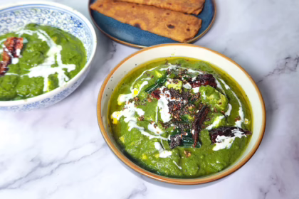 saag paneer in a bowl with paneer, spinach palak, curry leaves, spices, cream and chilli. Indian bread roti or naan.
